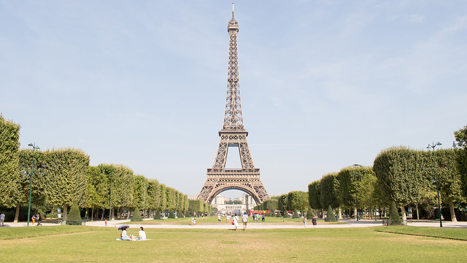 Green grass and hedges and people sat below the Eiffel Tower in Paris Green grass and hedges and people sat below the Eiffel Tower in Paris