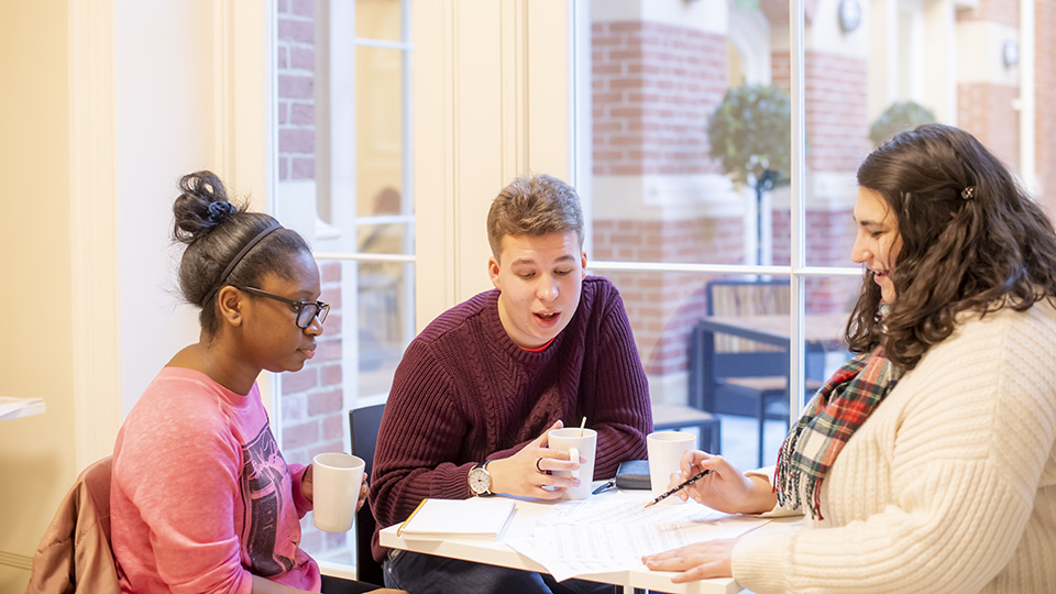 Two RCM postgraduate composer students with another student in discussion in the cafe Two RCM postgraduate composer students with another student in discussion in the cafe
