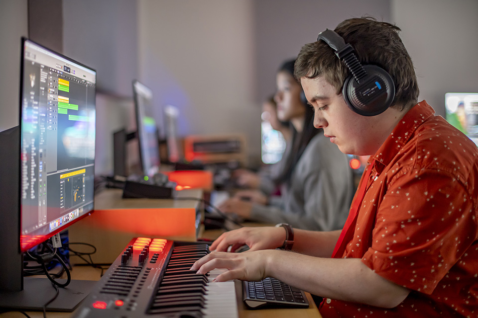 A student using a computer and keyboard to produce his composition A student using a computer and keyboard to produce his composition