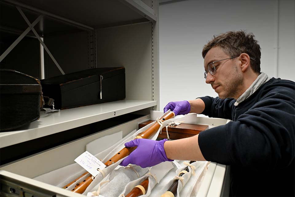 Wearing gloves and picking up a wooden flute from storage, in the RCM's Wolfson Centre