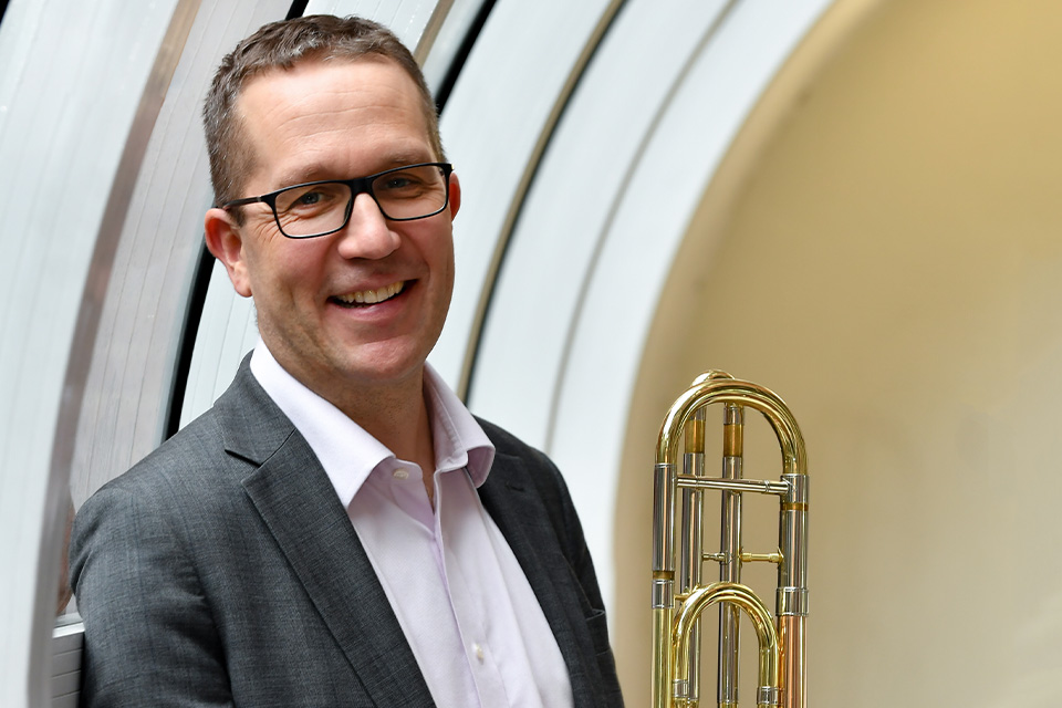 Amos Millar holds his trombone and smiles