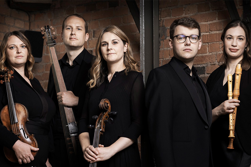 Ensemble Augelletti stand holding their instruments against a dark backdrop