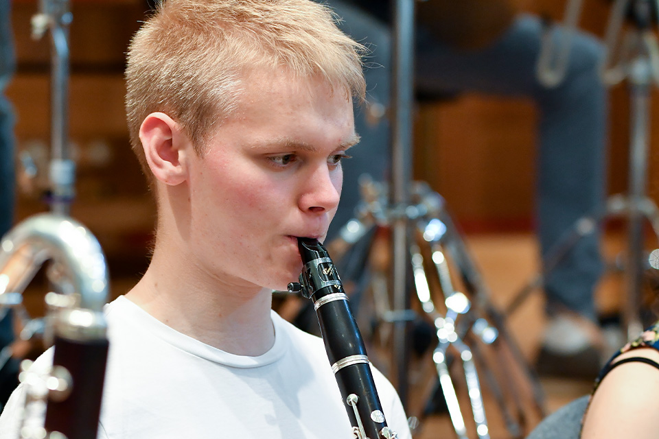 A young boy plays the clarinet in an orchestra