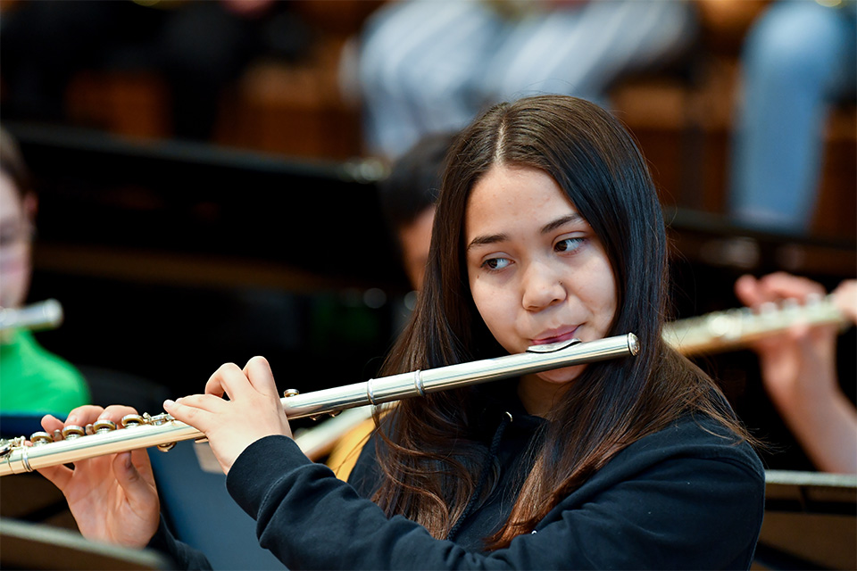 A young girl plays the flute