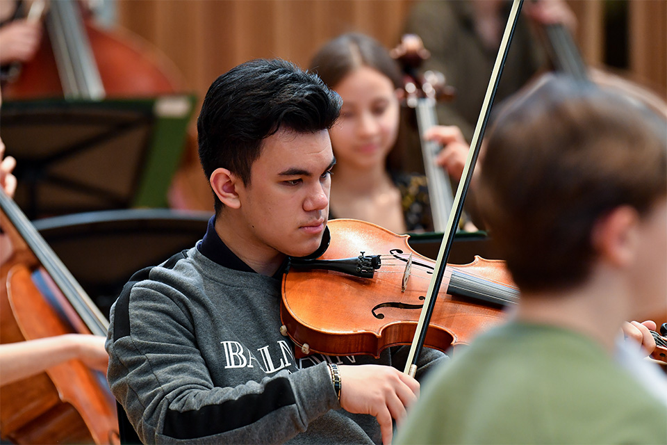 A young boy plays the viola in an orchestra