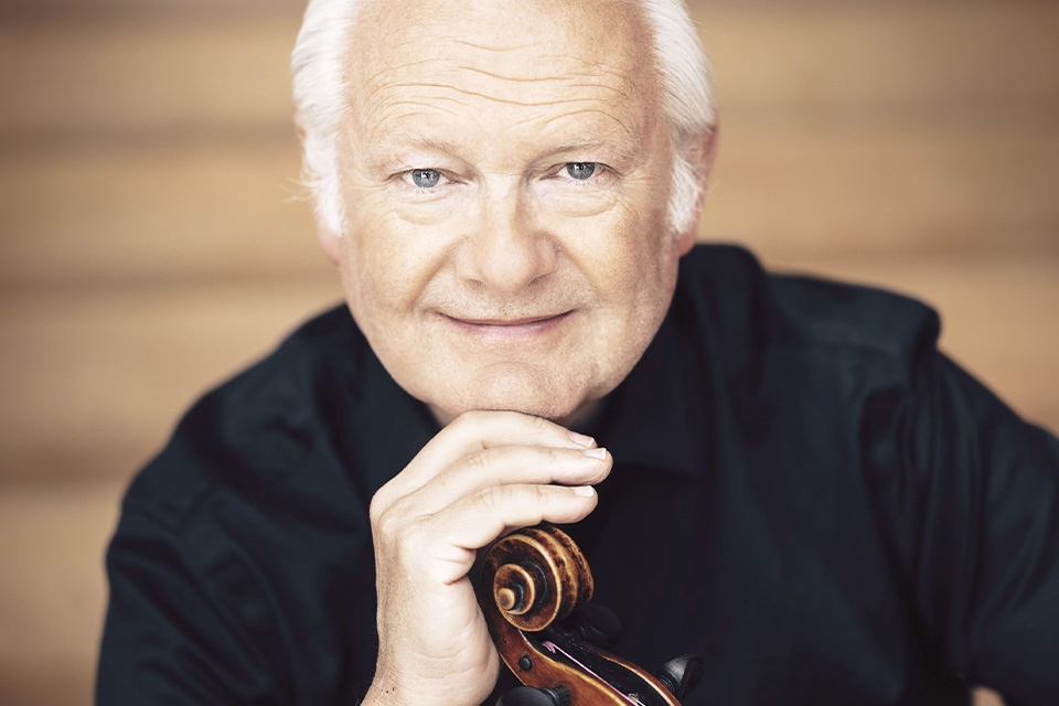 Lars Anders Tomter rests his hand on his viola and chin on his hand, smiling