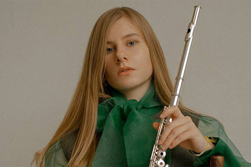 Maria Filippova wears a green blouse and holds her flute 