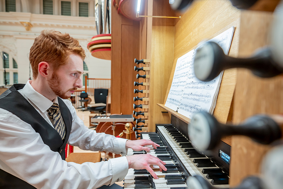 A young man wearing a white shirt plays the organ