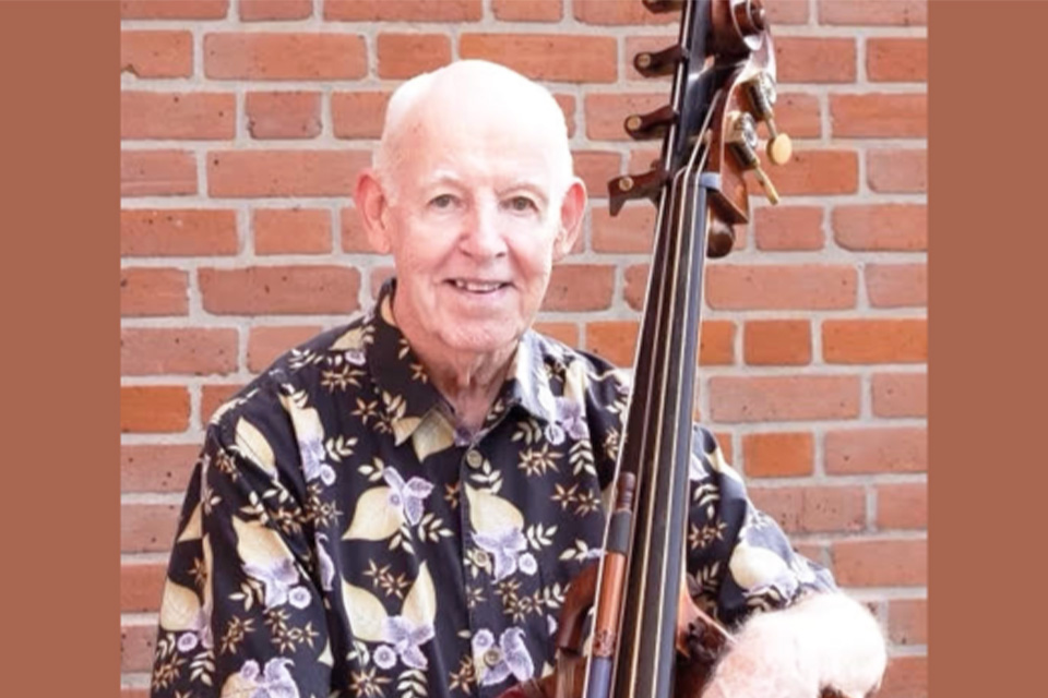 Paul Ellison holds his double bass, smiling