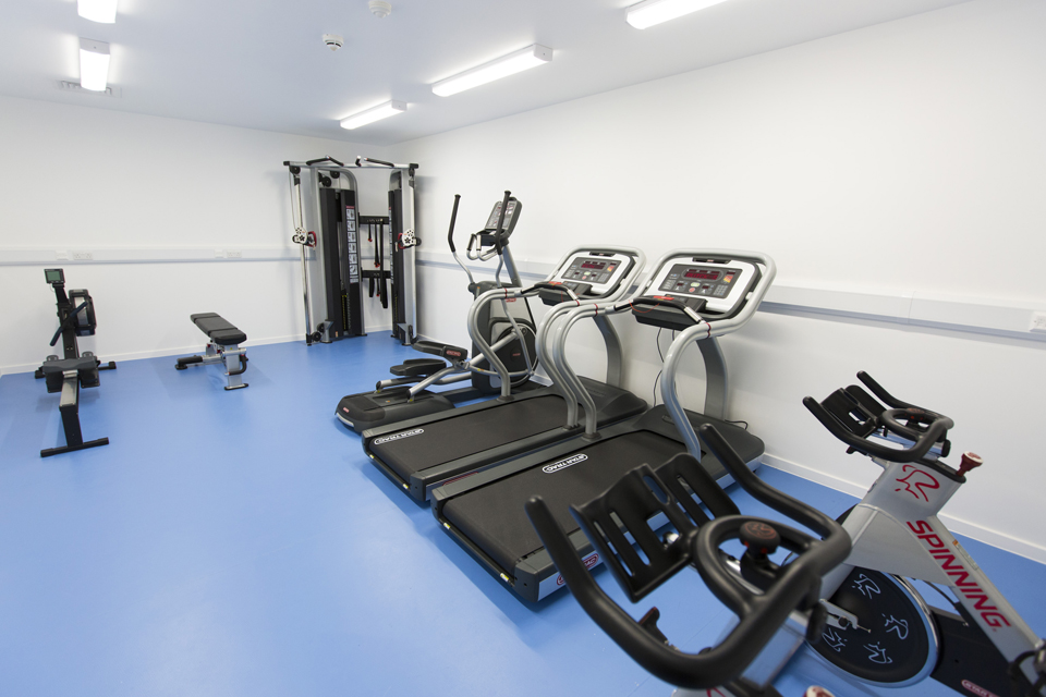 A line of gym equipment lining a wall in a gym.