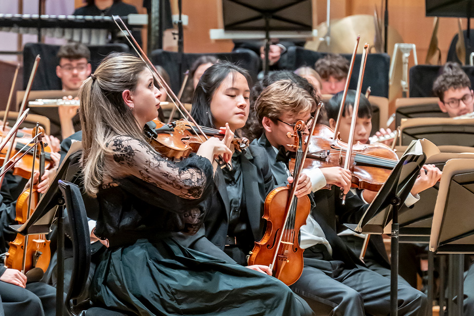A violinist leads an orchestra on stage