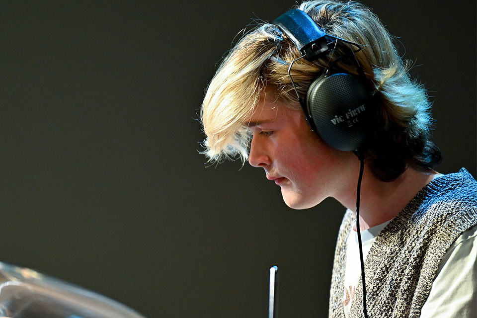 A boy wears headphones and looks down