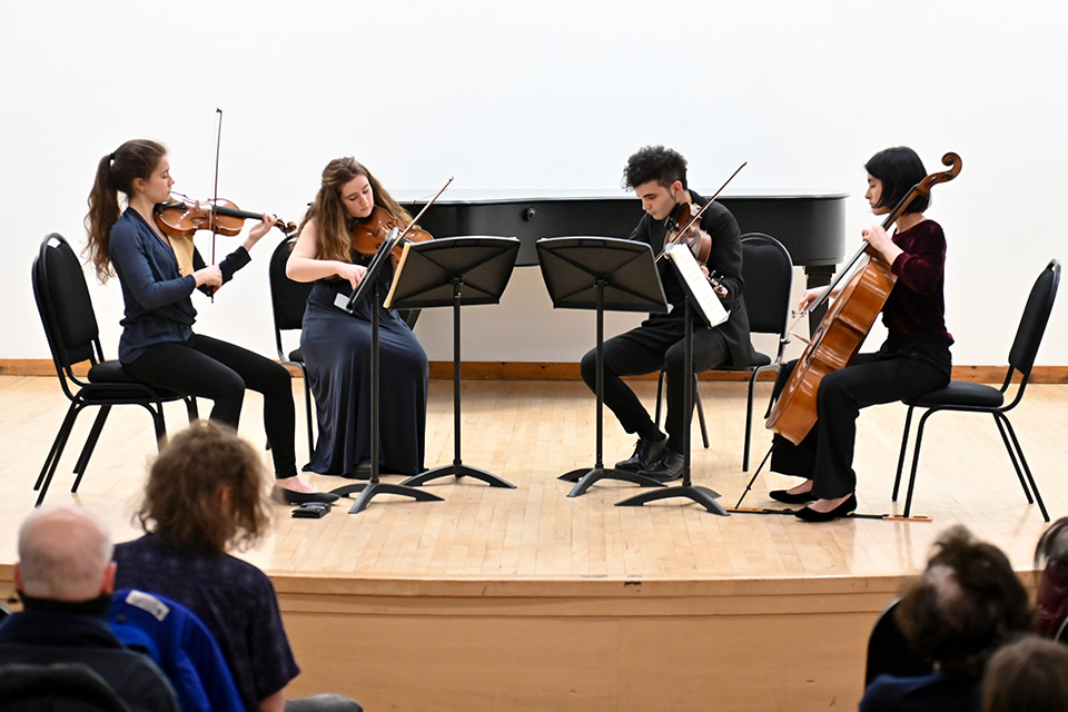 A string quartet performs on a brightly lit stage