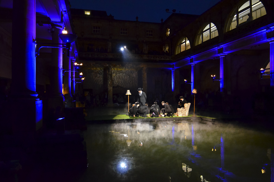 Students performing in a outdoor venue with pillars surrounding them in an evening performance.
