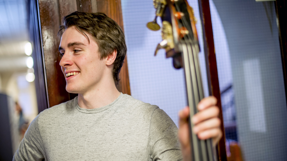 Double bassist standing in corridor
