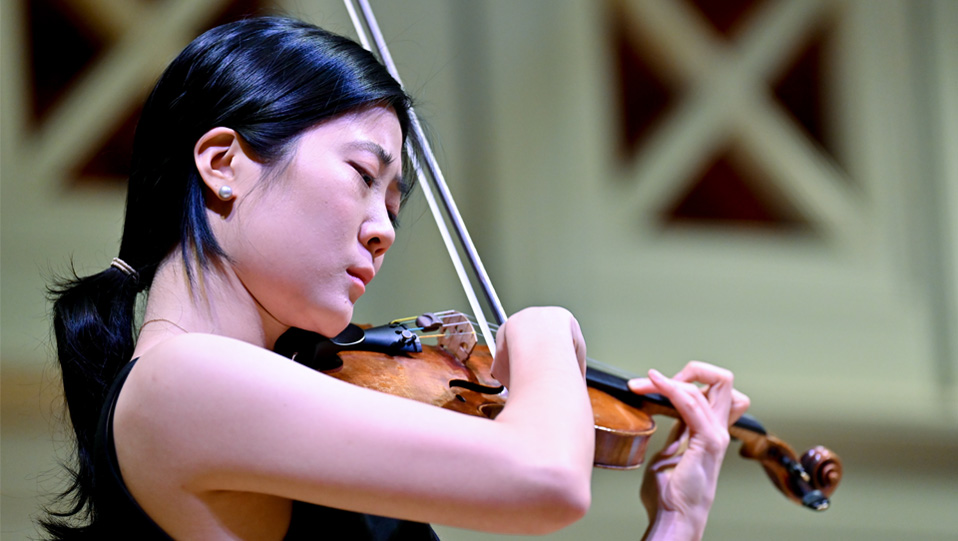 An Asian students playing the violin, surrounded by a bright environment. An Asian students playing the violin, surrounded by a bright environment.