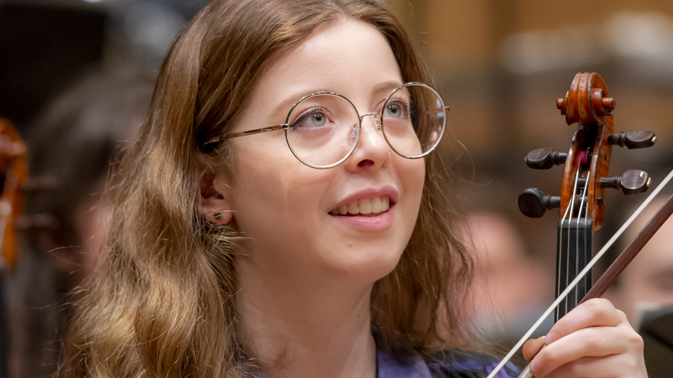 An RCM student holding their violin and looking up in rehearsals An RCM student holding their violin and looking up in rehearsals