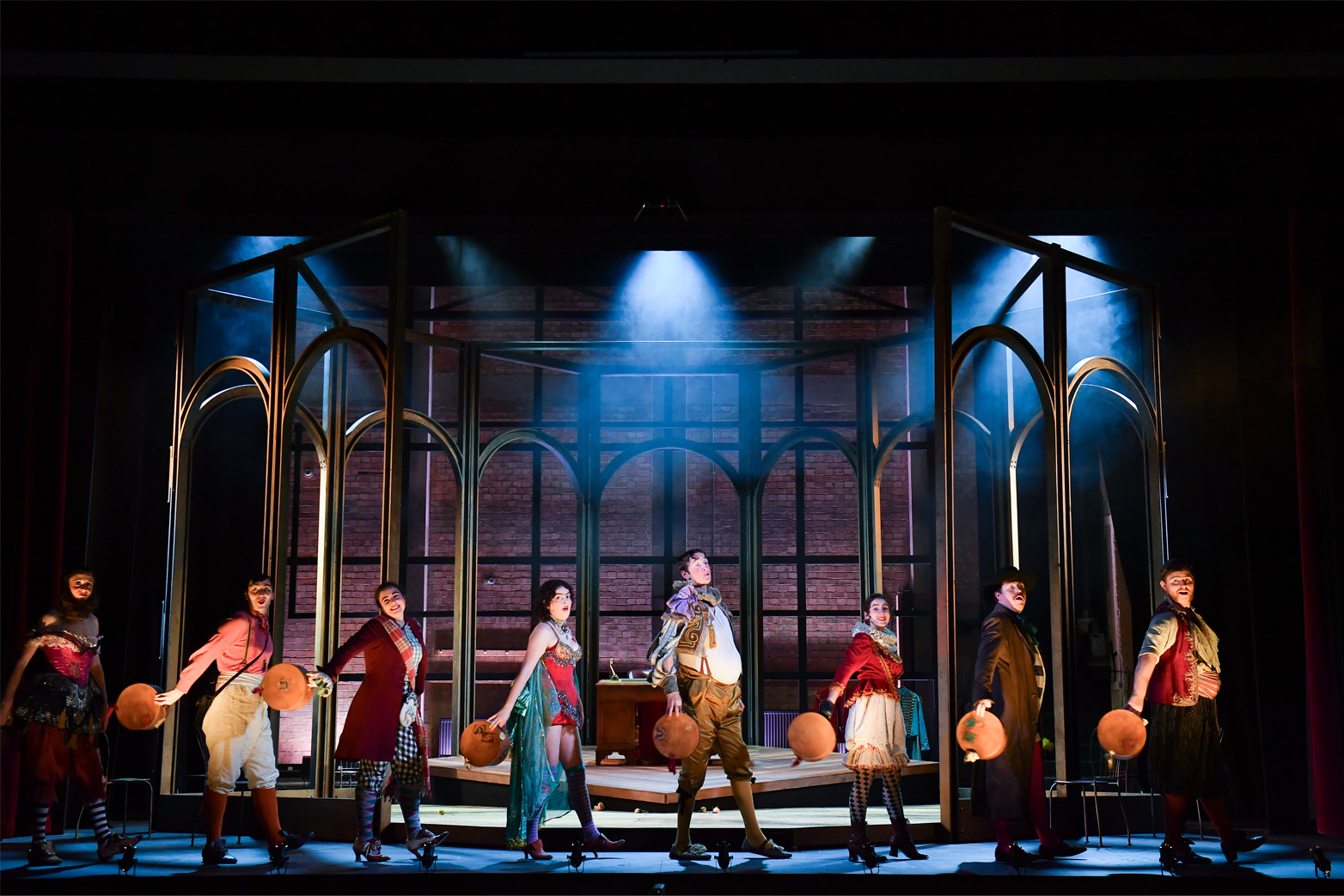 A group of students, wearing costumes, singing on stage in an opera performance of 'Barnum's Bird'.