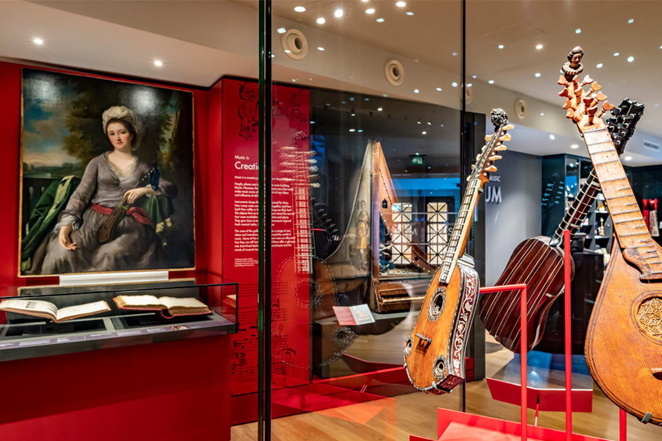 His Majesty The Emperor speaking with a man and viewing guitars in a museum