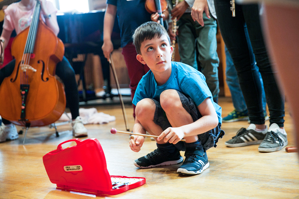 A young white boy, playing the glockenspiel in a case.